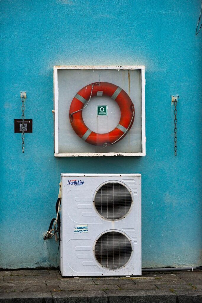 Outdoor wall with a lifebuoy and air conditioning unit on a bright blue background.